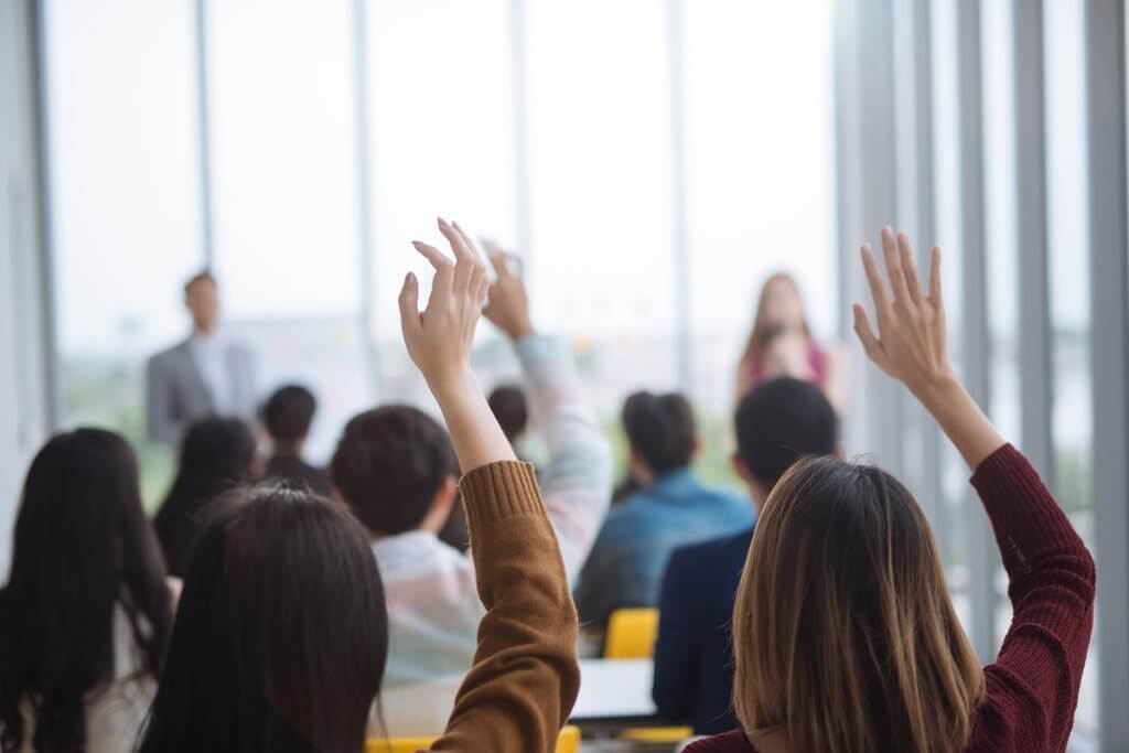 Students raising their hands in class