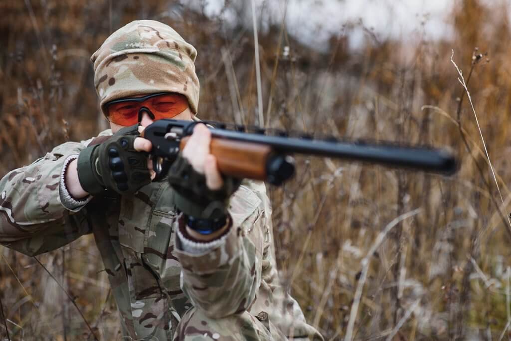 A man in the forest pointing a rifle
