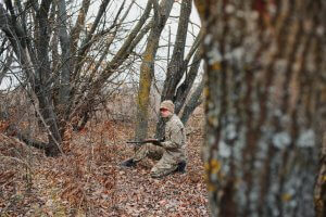 A hunter in the wild aiming with his rifle